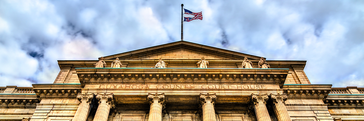 government building flying a flag on top with cloudy blue skies in the background