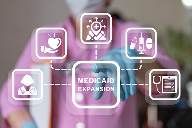 Doctor using virtual screen presses text: MEDICAID EXPANSION.